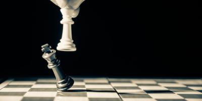 White Chess piece knocking over a black chess piece